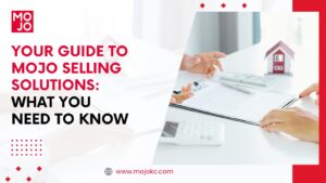 A professional from MoJo Selling Solutions discussing real estate strategies at a desk with a model house and financial documents.